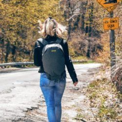 Woman wearing black jacket and jeans with backpack on back