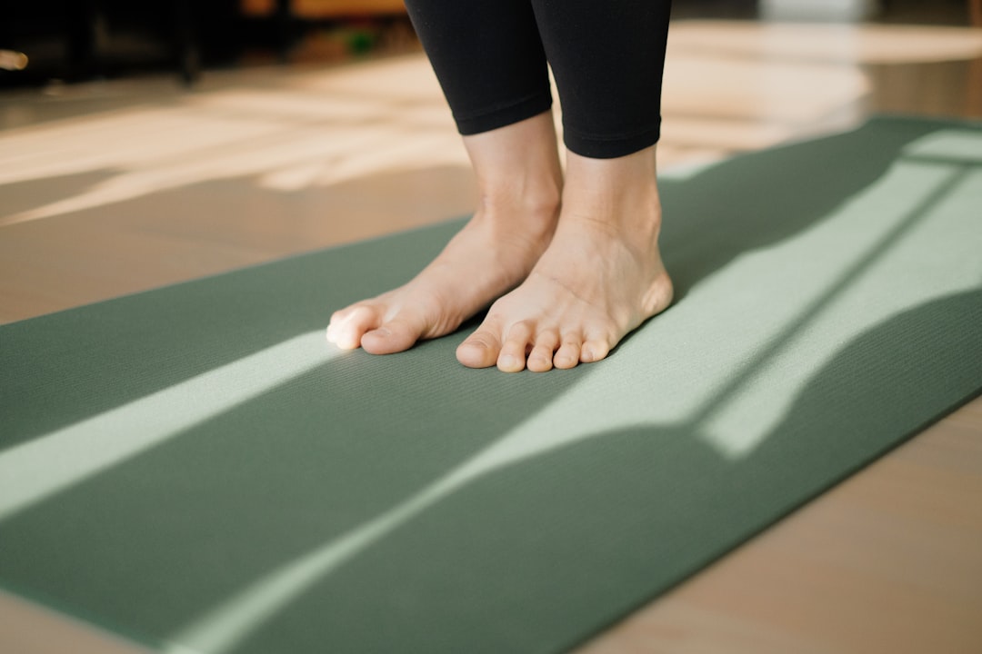 Photo by Junseong Lee a person standing on a yoga mat on the floor