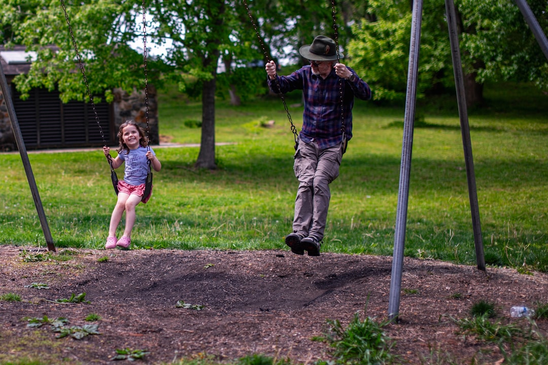 A man and a child swinging on playground swings